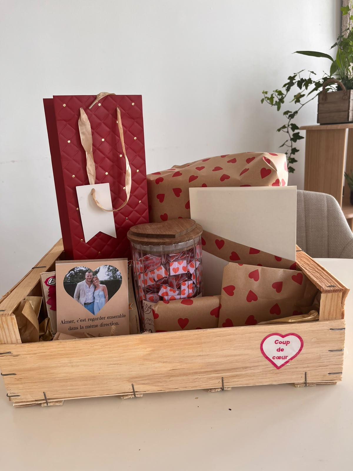 Ma box cadeau dans une caisse en bois, avec des emballages à cœurs et une carte personnalisée.